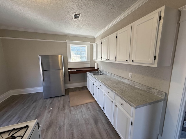 kitchen with visible vents, white cabinetry, freestanding refrigerator, dark wood finished floors, and crown molding