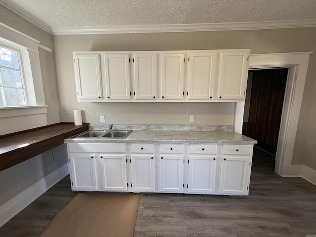 kitchen with crown molding, dark wood-style flooring, a sink, and white cabinets