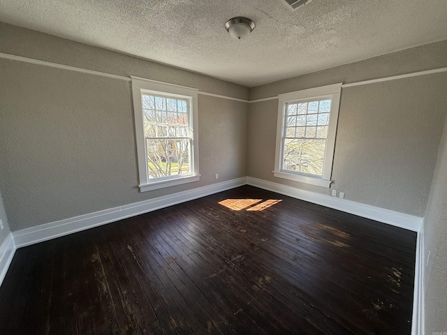 unfurnished room with dark wood-type flooring, a textured wall, a textured ceiling, and baseboards