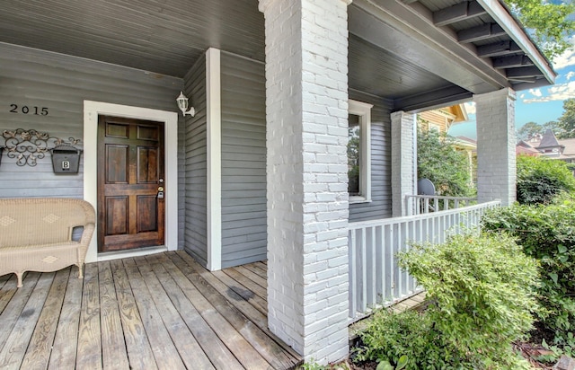 doorway to property with a porch and brick siding