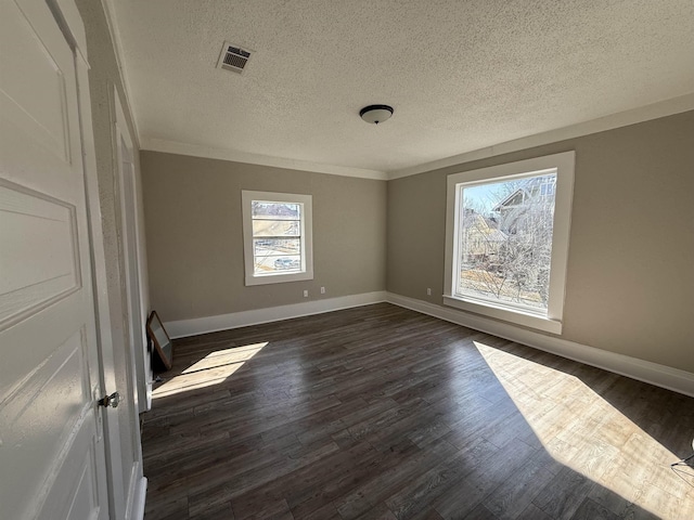 empty room featuring dark wood-style floors, baseboards, visible vents, and a textured ceiling