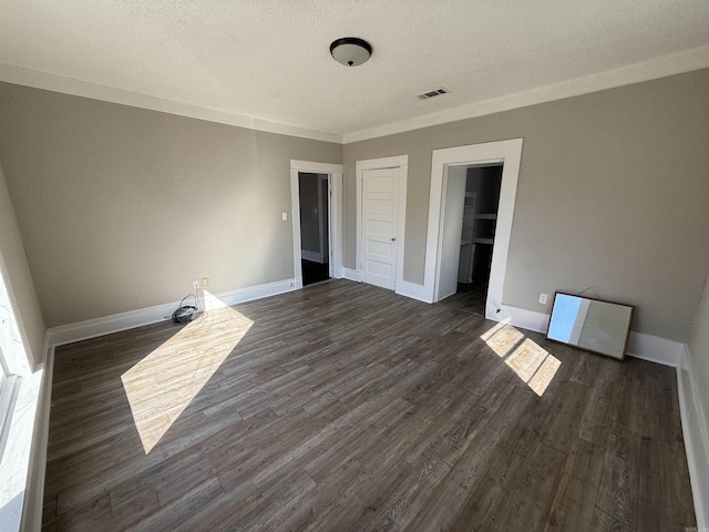 empty room with dark wood finished floors, visible vents, and baseboards