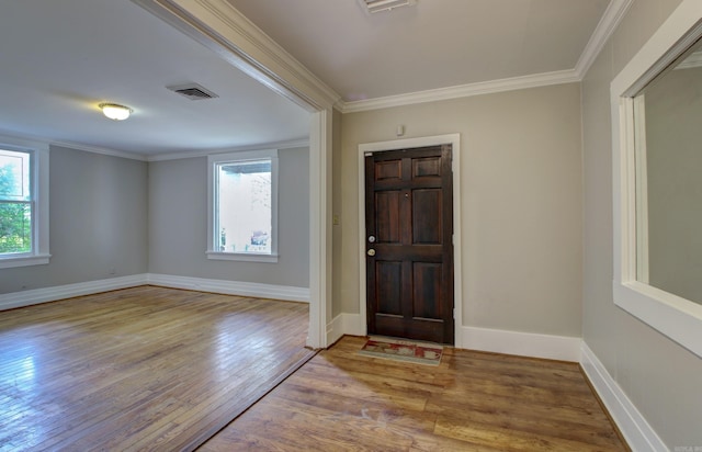 foyer with a wealth of natural light, visible vents, and crown molding