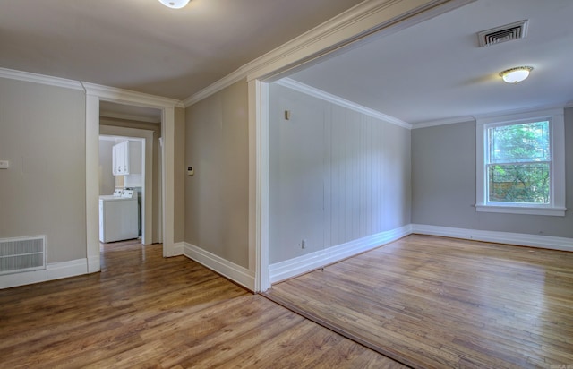 unfurnished room with visible vents, washer / clothes dryer, wood finished floors, and ornamental molding