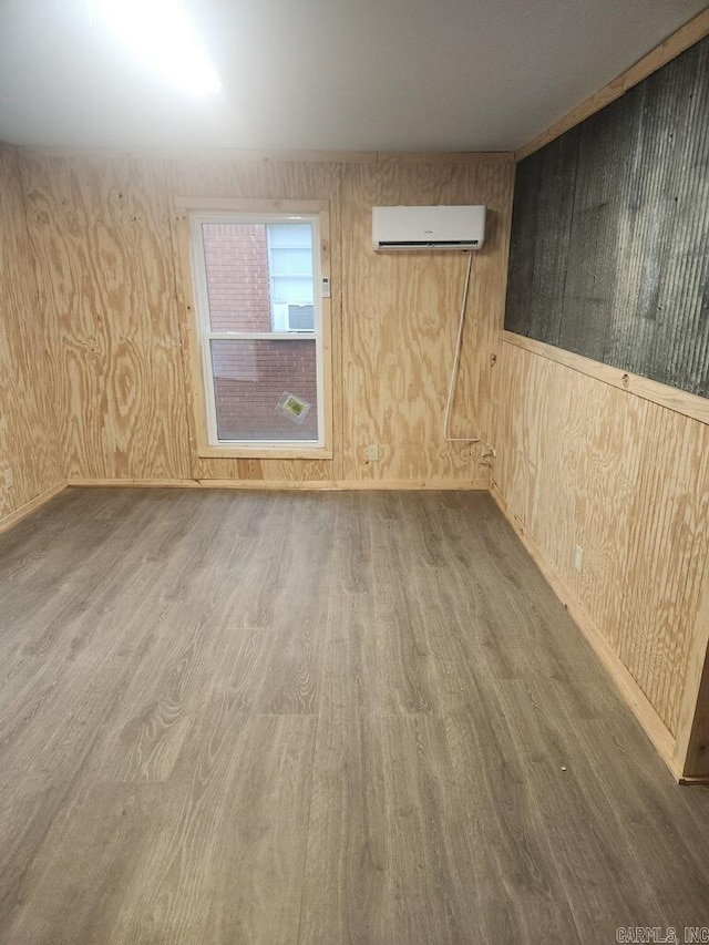 spare room with an AC wall unit and wood finished floors