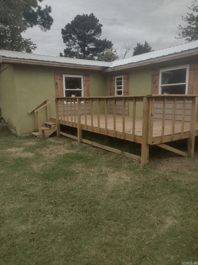 back of house featuring a deck, stucco siding, metal roof, and a yard