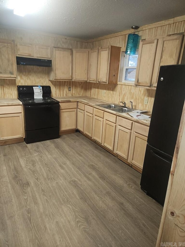 kitchen with under cabinet range hood, black appliances, light brown cabinetry, and a sink