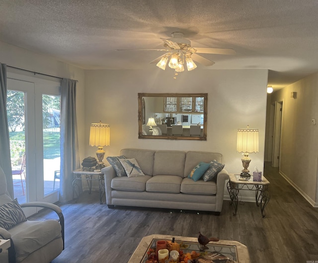 living room featuring a ceiling fan, a textured ceiling, baseboards, and wood finished floors