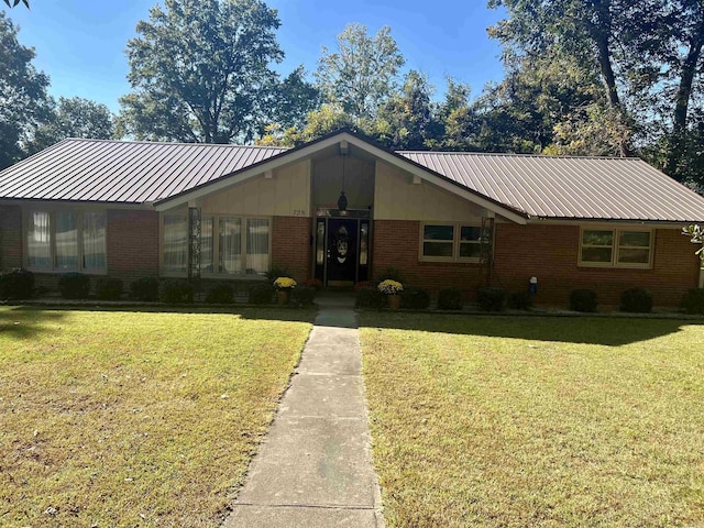 view of front of property with metal roof, a front lawn, board and batten siding, and brick siding