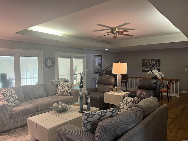 living area featuring a ceiling fan, a raised ceiling, and wood finished floors