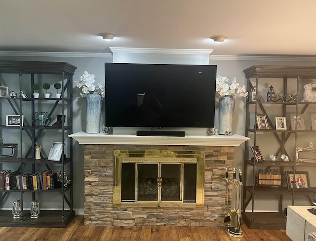 living area with a stone fireplace, ornamental molding, wood finished floors, and baseboards