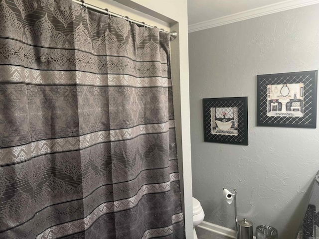 bathroom featuring a textured wall, toilet, baseboards, a shower with curtain, and crown molding