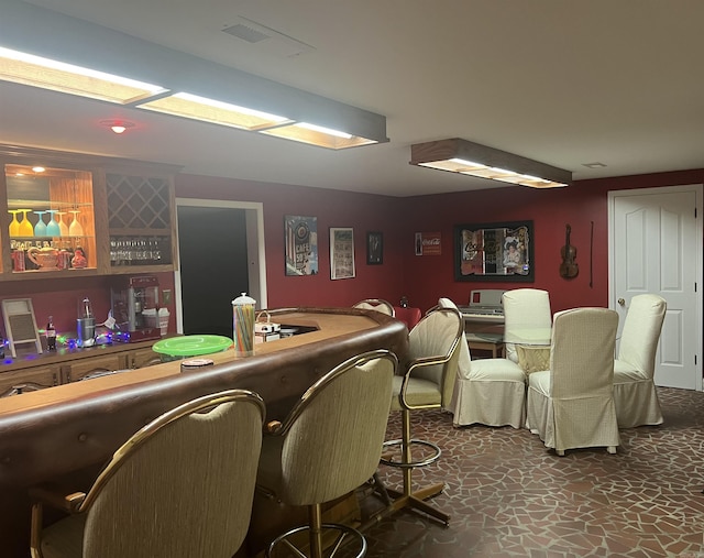 bar with stone finish floor, indoor wet bar, and visible vents