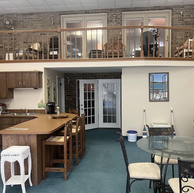 interior space featuring a patio, a balcony, outdoor dry bar, french doors, and brick siding