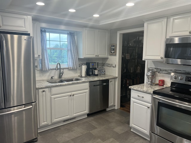 kitchen featuring stainless steel appliances, a sink, white cabinetry, ornamental molding, and tasteful backsplash