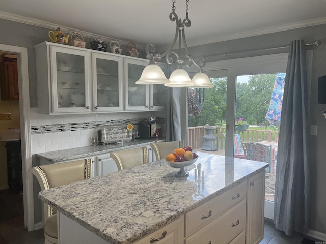 kitchen with light stone counters, backsplash, ornamental molding, glass insert cabinets, and white cabinetry