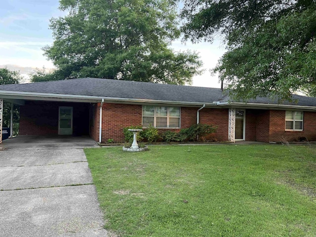 single story home with driveway, a shingled roof, an attached carport, a front yard, and brick siding