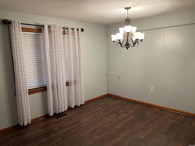 spare room with an inviting chandelier, baseboards, visible vents, and dark wood finished floors