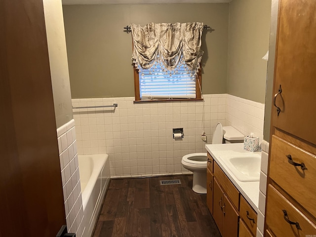 bathroom with visible vents, toilet, vanity, wood finished floors, and a bath