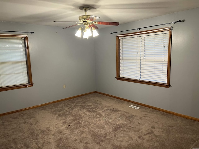 carpeted empty room featuring baseboards, visible vents, and ceiling fan