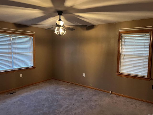 carpeted empty room featuring ceiling fan, visible vents, and baseboards