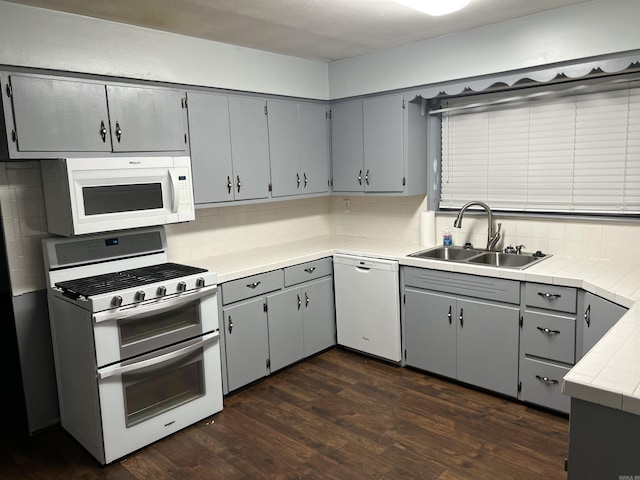 kitchen featuring tasteful backsplash, white appliances, a sink, and gray cabinetry