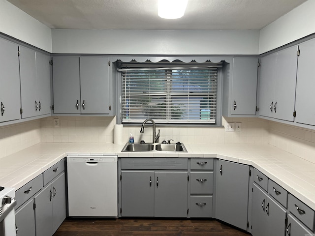 kitchen with gray cabinetry, dishwasher, backsplash, and a sink