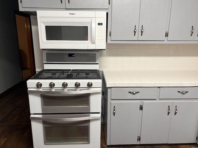 kitchen with white appliances, backsplash, and tile countertops