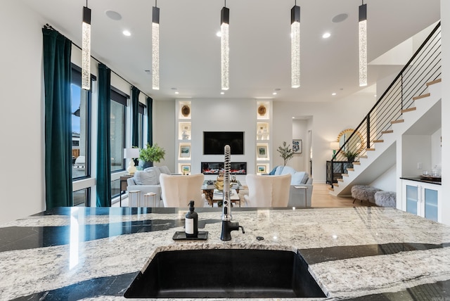 kitchen featuring open floor plan, hanging light fixtures, light stone counters, and recessed lighting