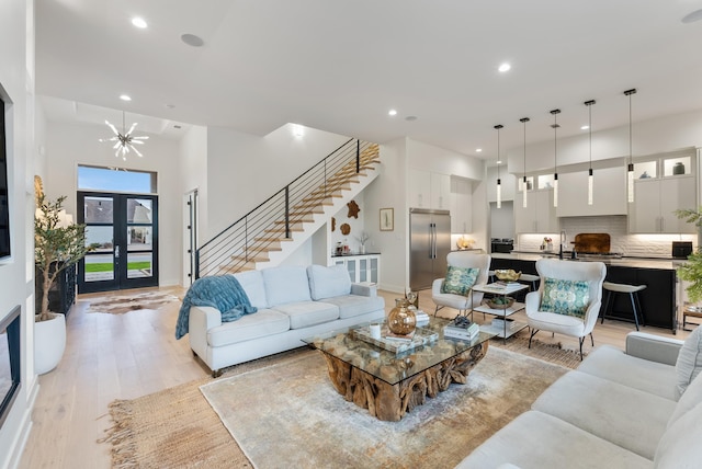 living area with recessed lighting, a notable chandelier, light wood-style flooring, and stairs