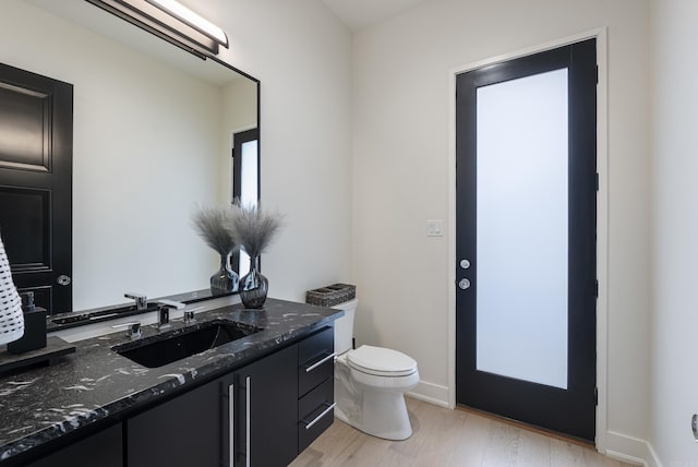 bathroom featuring toilet, baseboards, wood finished floors, and vanity