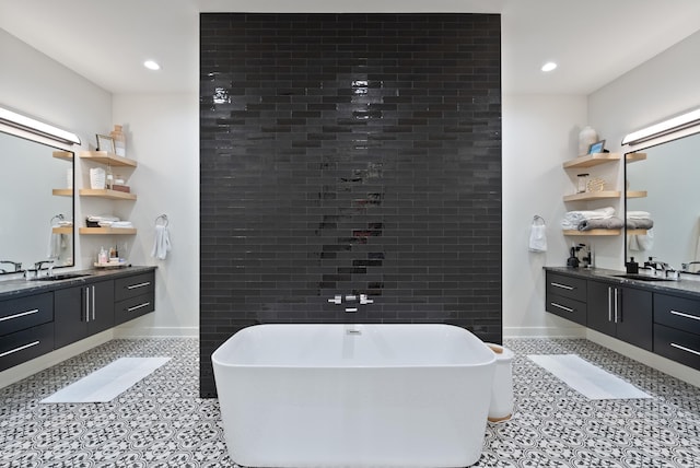 bathroom featuring a sink, a soaking tub, two vanities, and tile patterned flooring