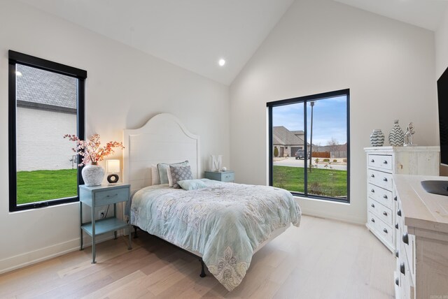 bedroom featuring high vaulted ceiling, light wood-type flooring, and baseboards