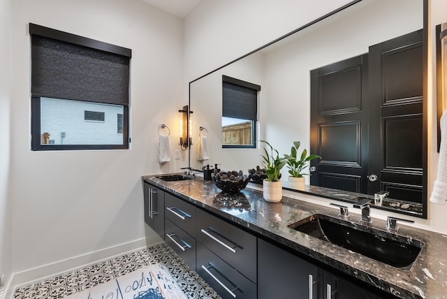 full bath featuring double vanity, tile patterned floors, a sink, and baseboards