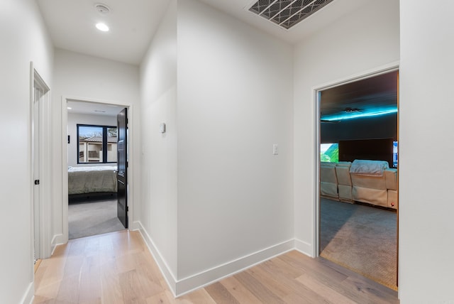 corridor with light wood-type flooring, baseboards, visible vents, and recessed lighting