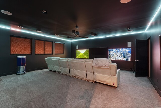 home theater featuring baseboards, a ceiling fan, and light colored carpet