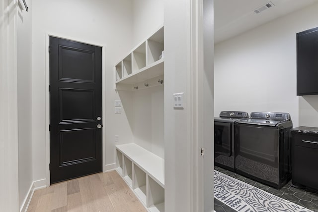 mudroom featuring light wood-style floors, baseboards, visible vents, and washing machine and clothes dryer