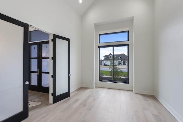 interior space with high vaulted ceiling, french doors, wood finished floors, and baseboards