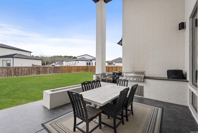 view of patio with exterior kitchen, outdoor dining area, a grill, and fence