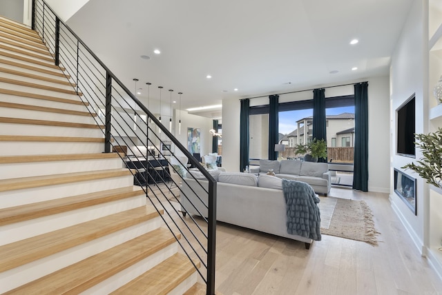 living room featuring light wood finished floors, a fireplace, stairway, and recessed lighting