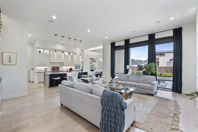 living room featuring light wood finished floors, baseboards, and recessed lighting