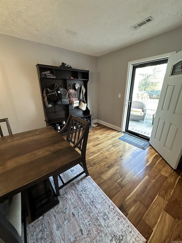 dining area featuring a textured ceiling, light wood-style flooring, visible vents, and baseboards