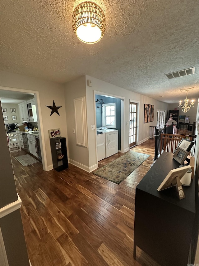 interior space featuring visible vents, dark wood-style flooring, an inviting chandelier, a textured ceiling, and washer and dryer