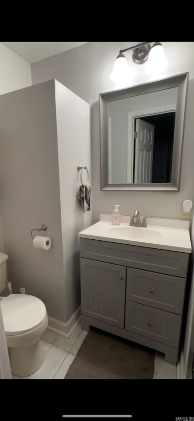 bathroom with toilet, baseboards, and vanity