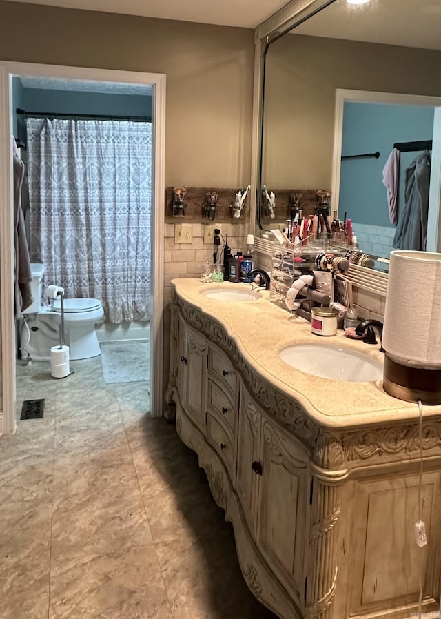 full bathroom featuring double vanity, a sink, and toilet