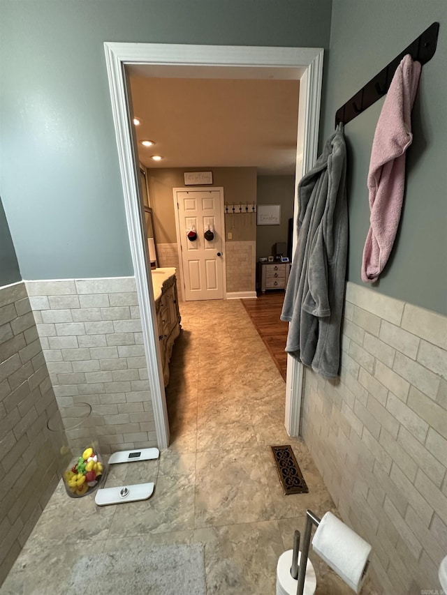 bathroom featuring visible vents, a wainscoted wall, tile walls, and vanity