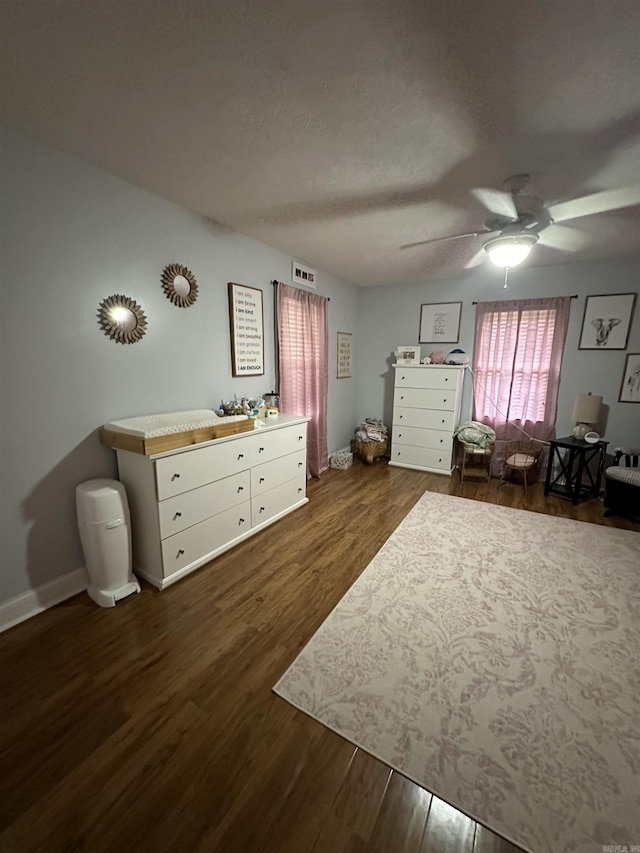 bedroom featuring baseboards, visible vents, ceiling fan, dark wood-style flooring, and a textured ceiling