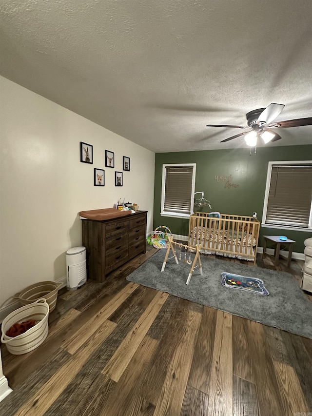 bedroom featuring a ceiling fan, a textured ceiling, baseboards, and wood finished floors