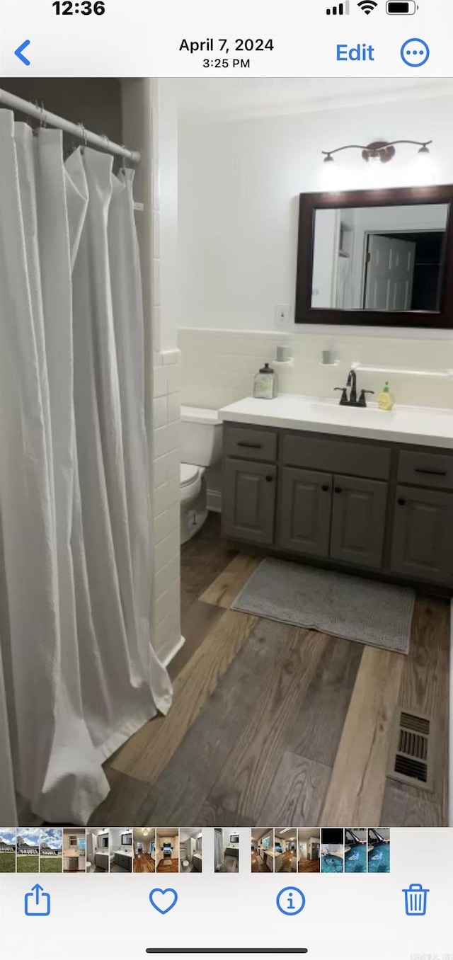 full bathroom featuring visible vents, a shower with shower curtain, toilet, wood finished floors, and vanity