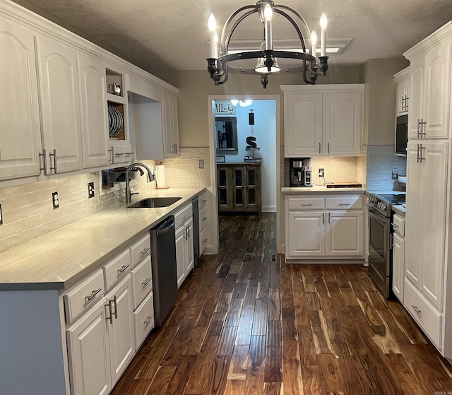 kitchen with dark wood-style floors, stainless steel appliances, white cabinets, a sink, and a chandelier